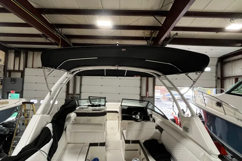 Slide: The Image of 2021 Sea Ray SDX 270 Outboard boat interior with black canopy in a storage facility. - 11