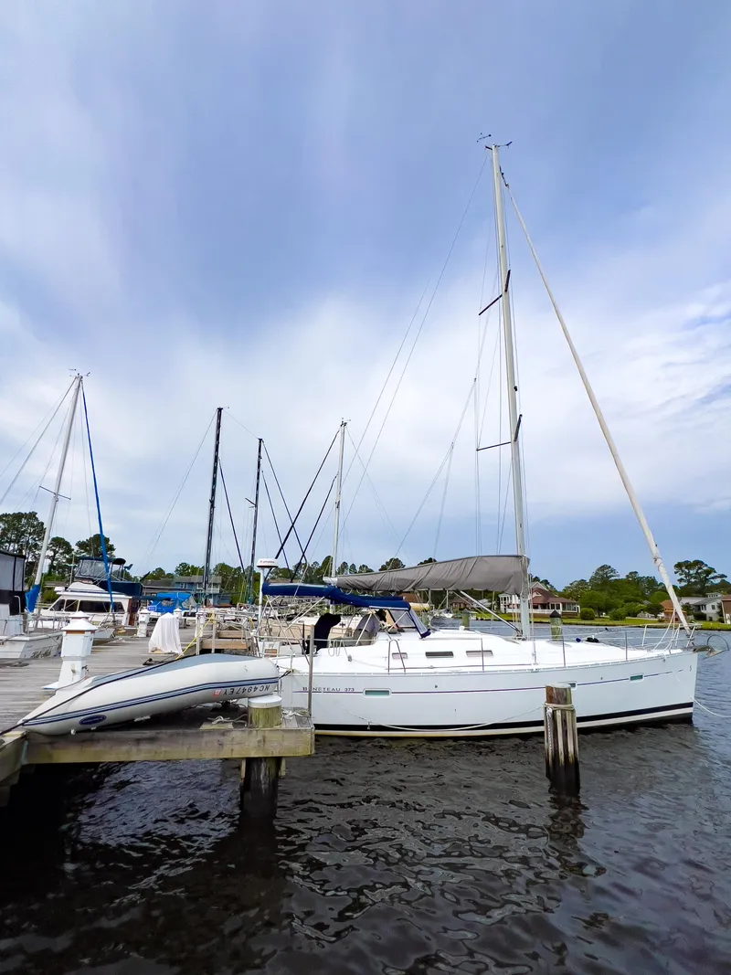 Slide: The Image of 2007 Beneteau 373 sailboat docked at a marina under a cloudy sky. - 2