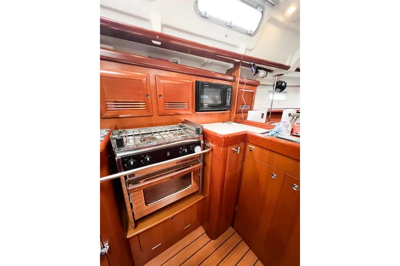 Slide: The Image of 2007 Beneteau 373 yacht kitchen with stove, oven, and microwave in wooden cabinetry. - 40