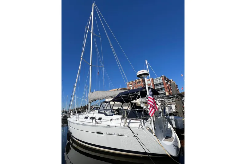 Slide: The Image of 2007 Beneteau 373 sailboat docked, featuring sleek design and American flag, under clear blue sky. - 5