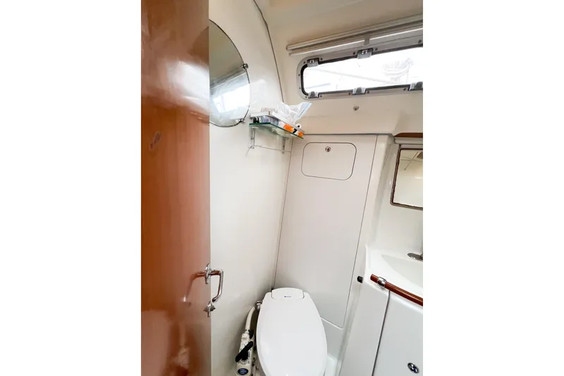Slide: The Image of 2007 Beneteau 373 yacht bathroom with toilet, mirror, and storage shelf. - 56