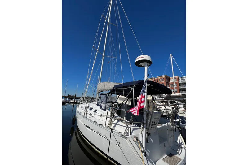 Slide: The Image of 2007 Beneteau 373 sailboat docked, featuring tall mast and American flag. - 8