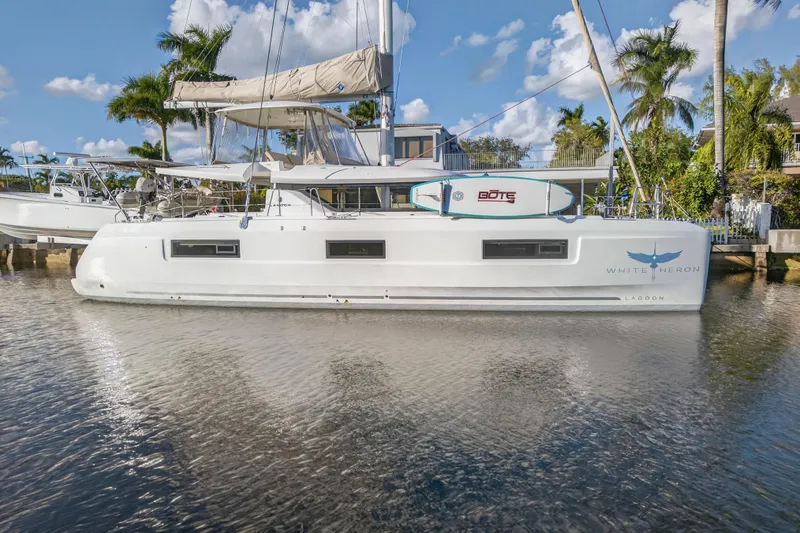 Slide: The Image of 2021 Lagoon 46 Owner's Version catamaran docked, featuring sleek design and paddleboard on deck. - 102