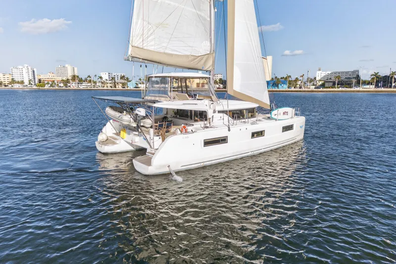 Slide: The Image of 2021 Lagoon 46 Owner's Version catamaran sailing near a coastal city. - 105