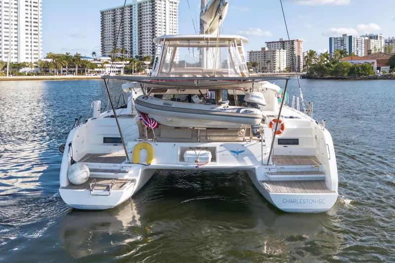 Slide: The Image of 2021 Lagoon 46 Owner's Version catamaran docked in a marina with cityscape background. - 108