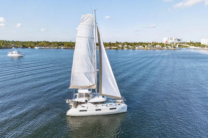 Slide: The Image of 2021 Lagoon 46 Owner's Version catamaran sailing on a calm, scenic waterway. - 113