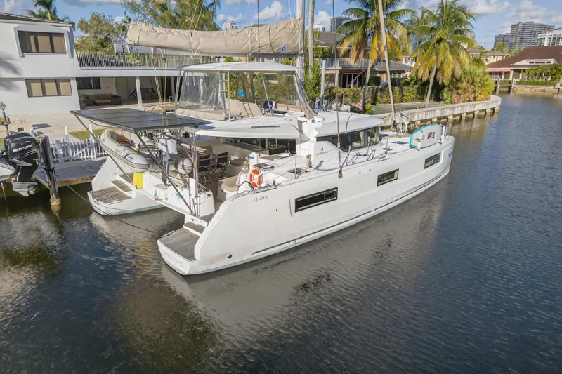 Slide: The Image of 2021 Lagoon 46 Owner's Version catamaran docked in a serene canal setting. - 117