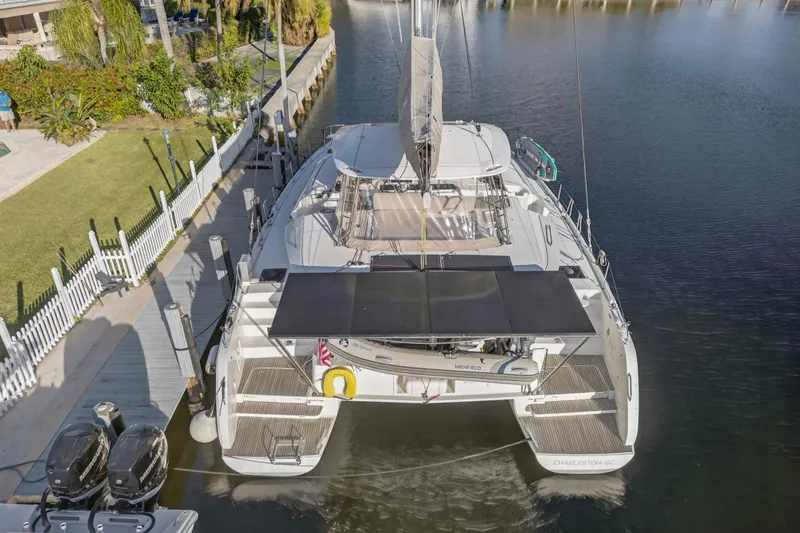 Slide: The Image of Aerial view of 2021 Lagoon 46 Owner's Version catamaran docked by a lush waterfront. - 119