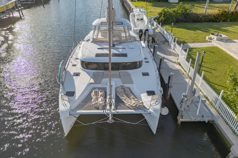 Slide: The Image of 2021 Lagoon 46 Owner's Version catamaran docked in a serene marina setting. - 120