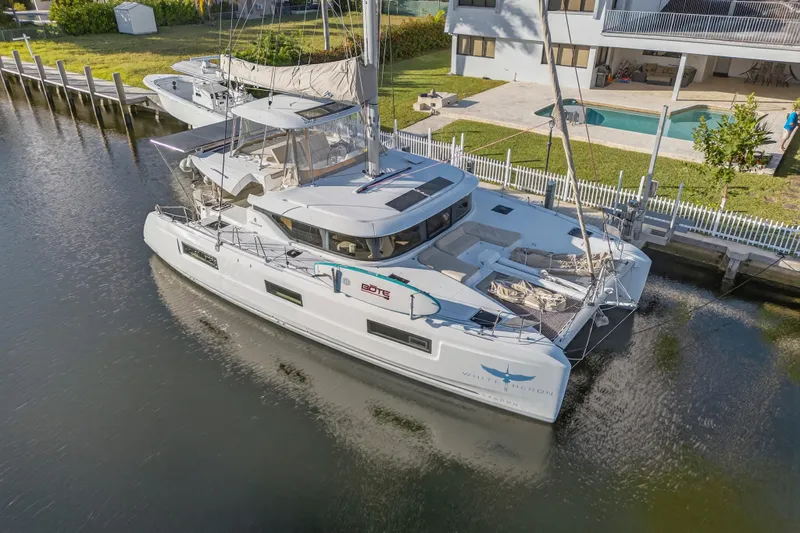 Slide: The Image of 2021 Lagoon 46 Owner's Version catamaran docked by a waterfront property. - 121
