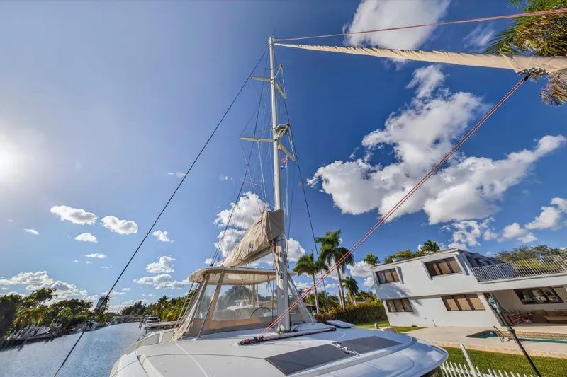 Slide: The Image of 2021 Lagoon 46 Owner's Version catamaran sailing under a clear blue sky near waterfront homes. - 45