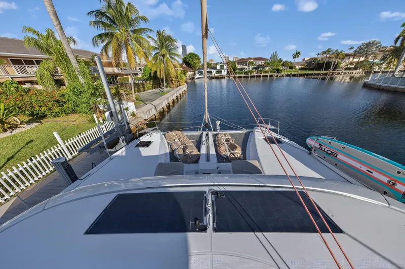 Slide: The Image of Lagoon 46 Owner's Version 2021 catamaran docked by a scenic canal with palm trees. - 46