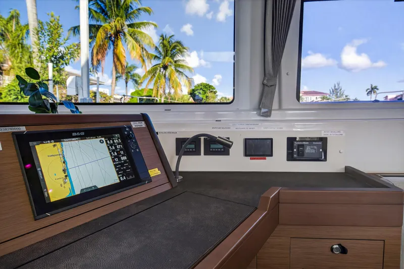 Slide: The Image of Navigation station inside 2021 Lagoon 46 Owner's Version catamaran with tropical view. - 61