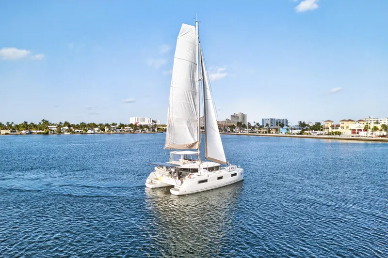 Slide: The Image of 2021 Lagoon 46 Owner's Version catamaran sailing in a sunny coastal harbor. - 107