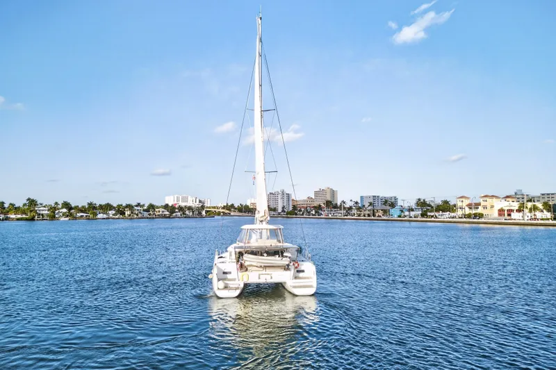 Slide: The Image of 2021 Lagoon 46 Owner's Version catamaran sailing in a sunny coastal cityscape. - 109