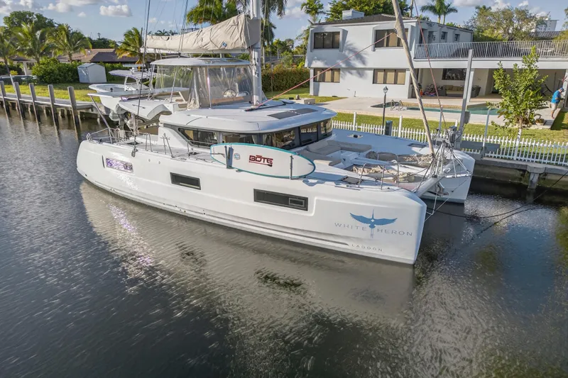Slide: The Image of 2021 Lagoon 46 Owner's Version catamaran docked by a waterfront home. - 116