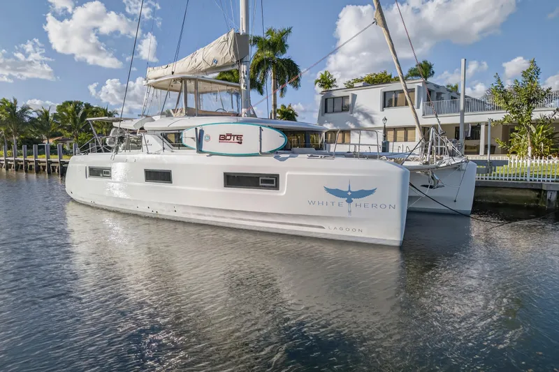 Slide: The Image of 2021 Lagoon 46 Owner's Version catamaran docked by waterfront home, sunny day. - 3