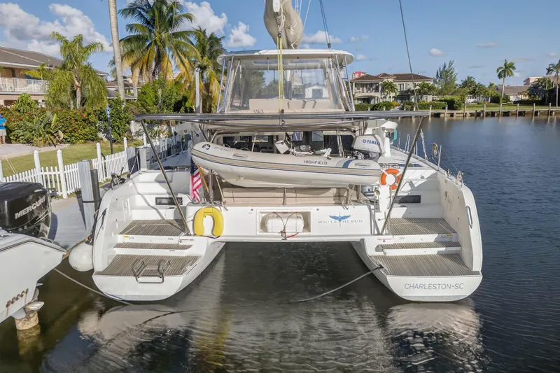Slide: The Image of 2021 Lagoon 46 Owner's Version catamaran docked in a scenic marina setting. - 4