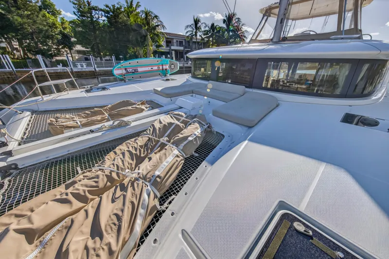 Slide: The Image of 2021 Lagoon 46 Owner's Version catamaran with sunbathing area and paddleboard, docked in a tropical setting. - 41