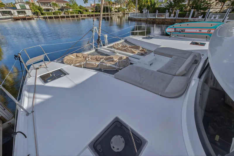 Slide: The Image of 2021 Lagoon 46 Owner's Version catamaran with spacious deck and seating, docked by the water. - 44
