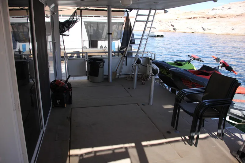 Slide: The Image of 2007 Sumerset Steel Away houseboat deck with chairs, jet skis, and scenic water view. - 11