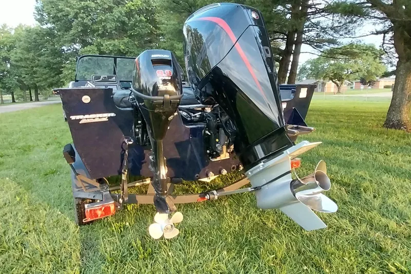 Slide: The Image of 2025 Tracker Targa V-19 WT boat with dual outboard motors on grassy area. - 34