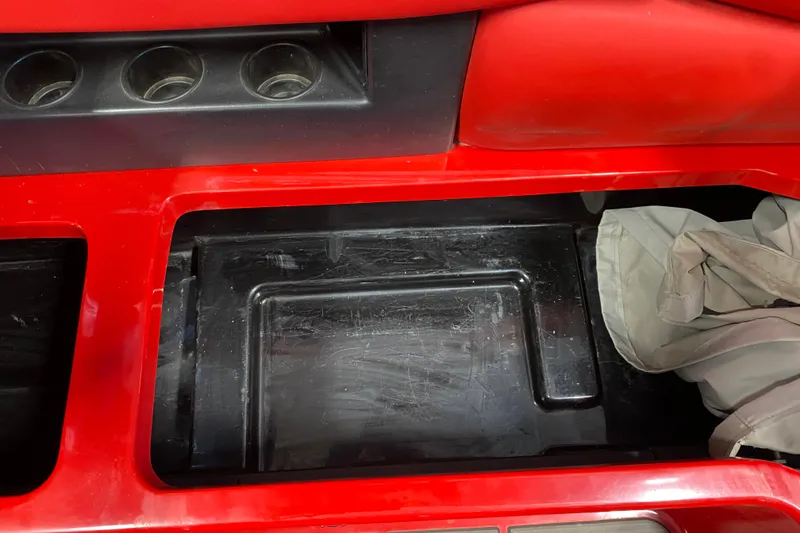 Slide: The Image of Red interior storage compartment of a 2019 Axis A24 boat with cup holders. - 12