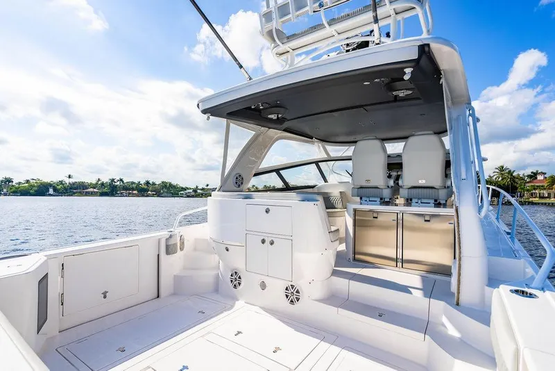 Slide: The Image of 2022 Intrepid 477 Evolution yacht interior with seating and storage, overlooking serene waters. - 5