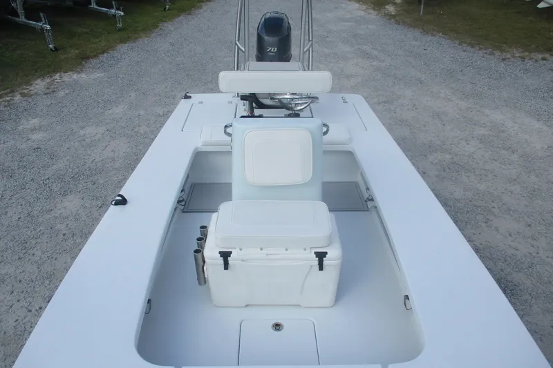 Slide: The Image of 2022 Brackish 19 boat interior with seating and storage on gravel path. - 9