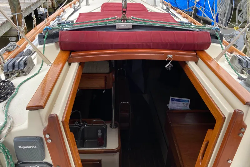 Slide: The Image of 1990 Pacific Seacraft 34 Voyager sailboat interior with wood finish and red cushions. - 14
