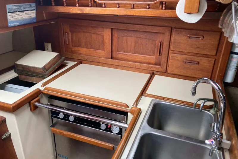 Slide: The Image of Galley kitchen in 1990 Pacific Seacraft 34 Voyager sailboat with wood cabinetry and stainless steel sink. - 18