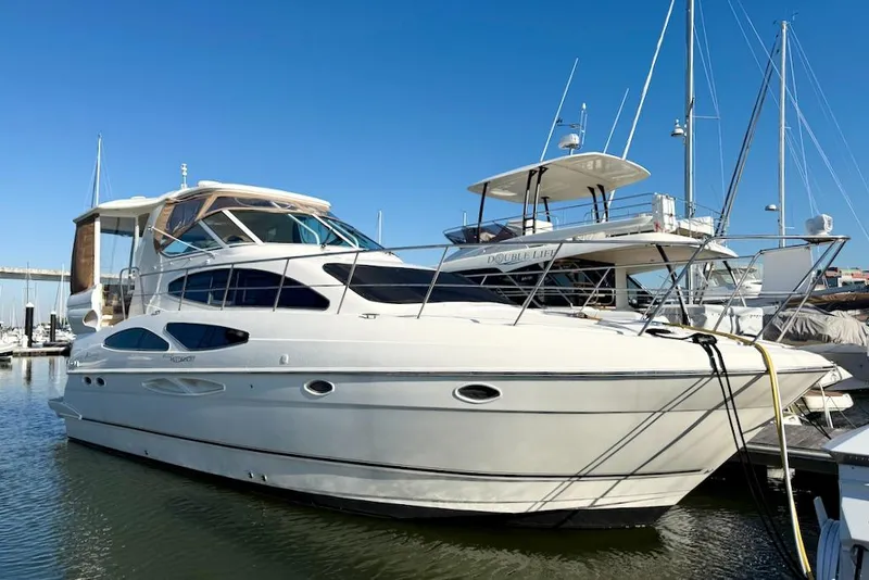 Slide: The Image of 2006 Cruisers Yachts 415 Express Motoryacht docked in marina under clear blue sky. - 4
