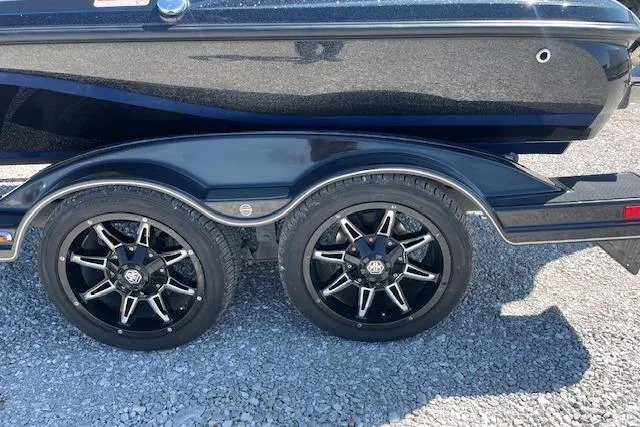 Slide: The Image of 2018 Nitro Z21 boat trailer with black alloy wheels on gravel surface. - 4