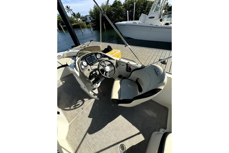 Slide: The Image of 2022 Stingray SC192 boat interior with steering wheel and dashboard, docked by water. - 26