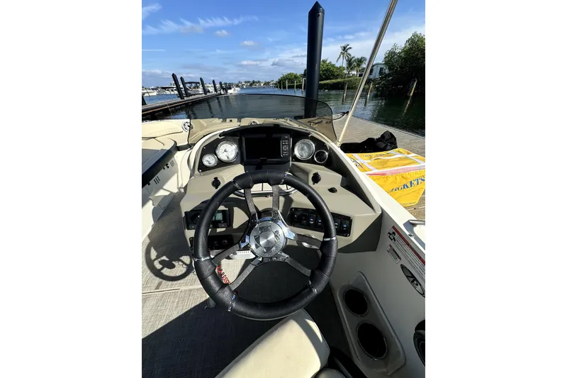 Slide: The Image of 2022 Stingray SC192 boat dashboard with steering wheel, gauges, and controls by the water. - 4