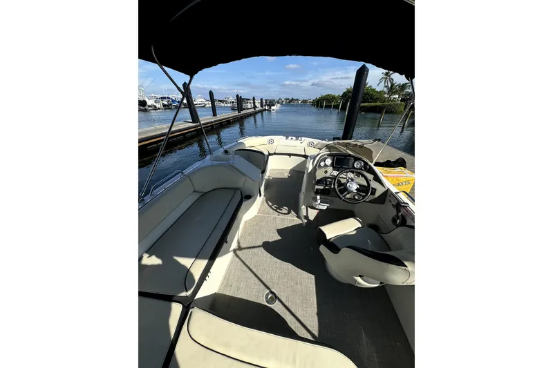 Slide: The Image of 2022 Stingray SC192 boat interior with steering wheel, docked by a scenic waterfront. - 7