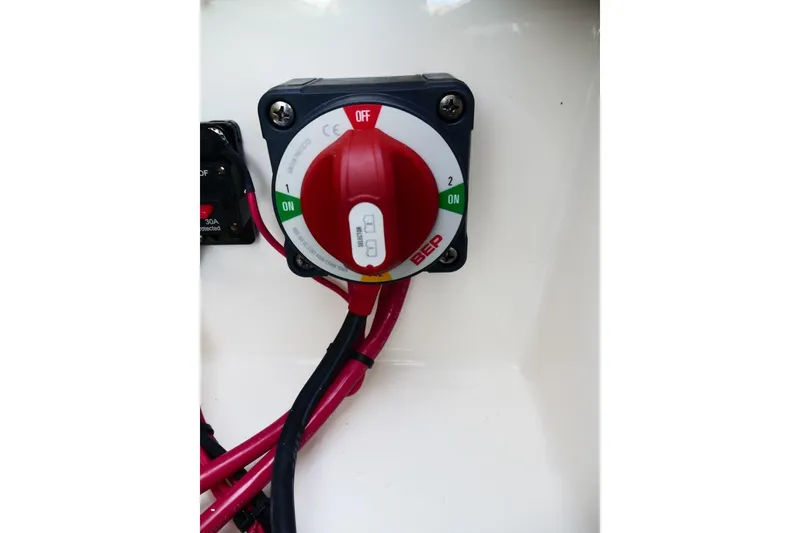 Slide: The Image of Red battery switch on Avenger AV26, 2026 model, with connected cables. - 60