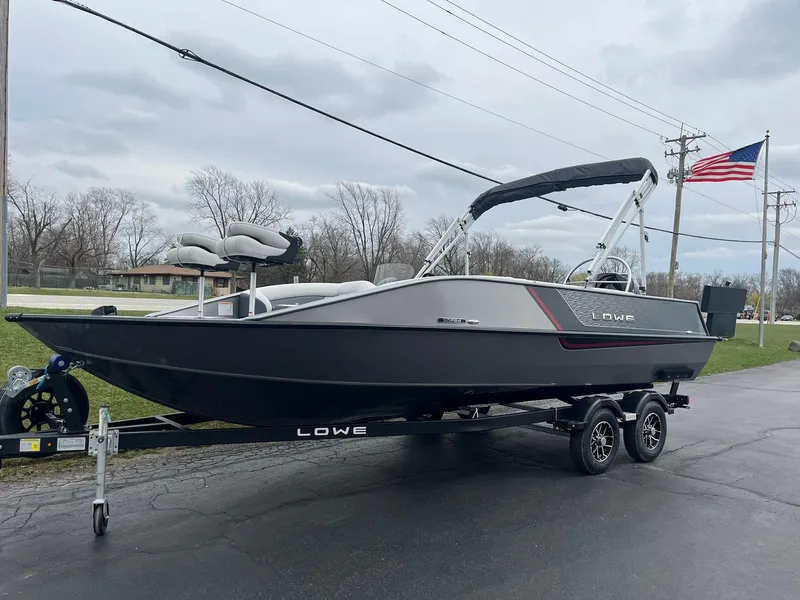 Slide: The Image of 2025 Lowe Deck SD224 boat on trailer, parked outdoors with American flag in background. - 4