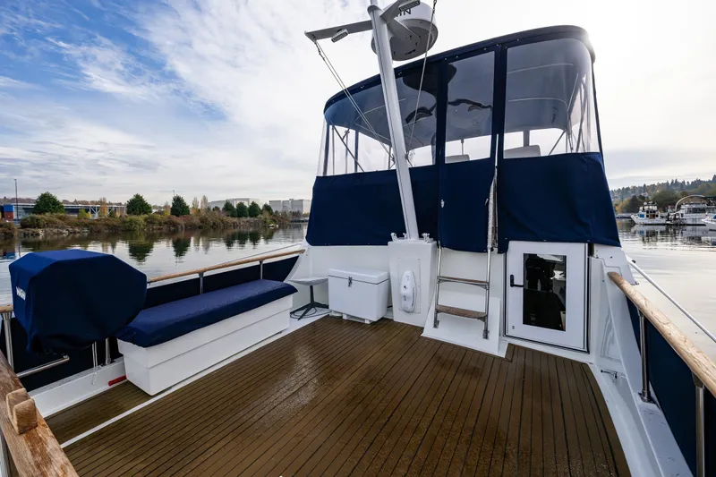 Slide: The Image of 1991 Tollycraft 48 Cockpit Motor Yacht on calm water, featuring spacious deck and seating area. - 18