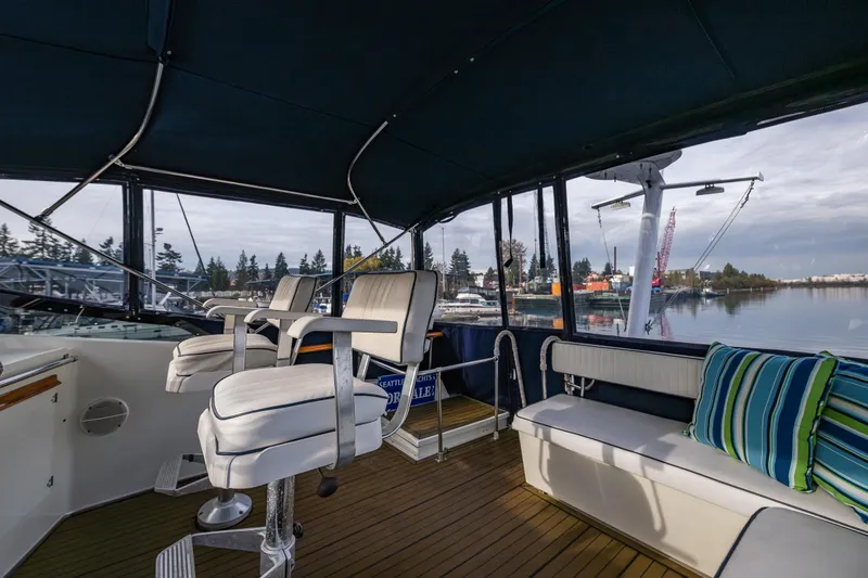 Slide: The Image of 1991 Tollycraft 48 Cockpit Motor Yacht interior with seating, helm chairs, and scenic marina view. - 21