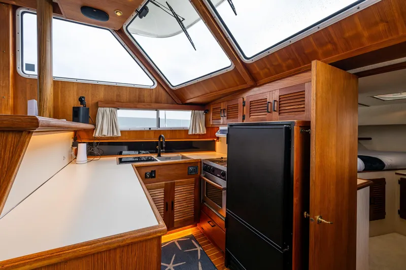 Slide: The Image of Interior of 1991 Tollycraft 48 Cockpit Motor Yacht kitchen with wood cabinetry and modern appliances. - 31