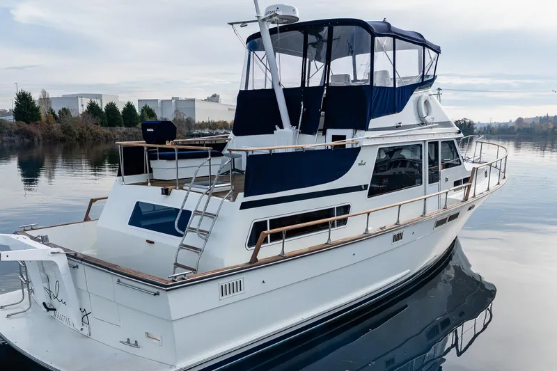 Slide: The Image of 1991 Tollycraft 48 Cockpit Motor Yacht on calm water, featuring spacious deck and blue canopy. - 7