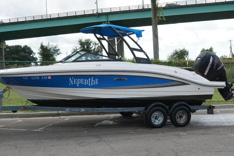 Slide: The Image of 2015 Sea Ray 21 SPX OB boat on trailer, blue and white design, under a bridge. - 8