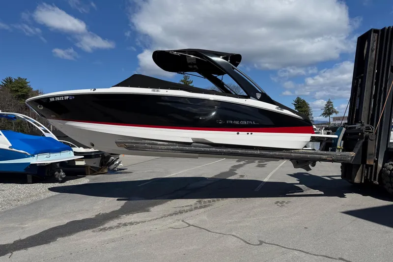 Slide: The Image of 2025 Regal LS6 boat lifted by forklift under clear blue sky. - 20