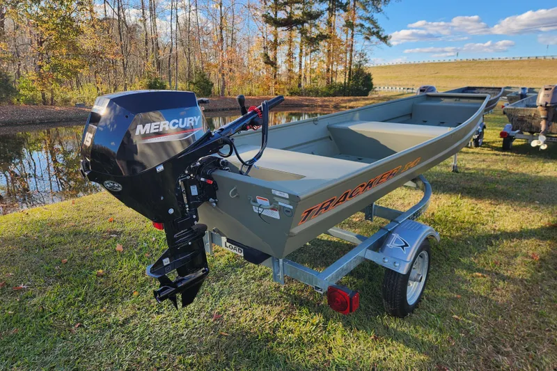Slide: The Image of 2026 Tracker Grizzly 1436 Utility boat with Mercury engine on trailer by a pond. - 3