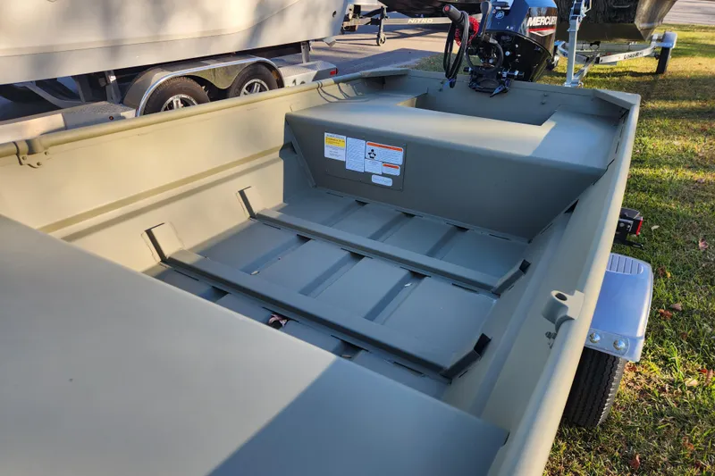 Slide: The Image of 2026 Tracker Grizzly 1436 Utility boat interior with motor, parked on grass. - 6