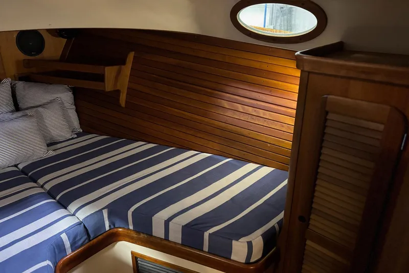 Slide: The Image of Cozy cabin interior of 2003 Hinckley 36 Picnic Boat EP with striped bedding and wooden paneling. - 12
