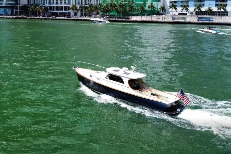 The Image of 2003 Hinckley 36 Picnic Boat EP cruising on green water near a cityscape. - 0