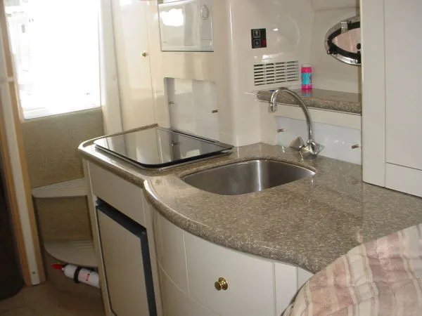 Slide: The Image of 1998 Maxum 3000SCR boat interior kitchen with sink, stove, and compact fridge. - 12