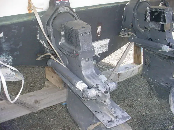 Slide: The Image of 1998 Maxum 3000SCR boat outdrive on wooden blocks, showing wear and corrosion. - 14